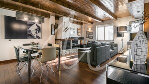 Ein modernes Wohnzimmer mit Holzboden, einem Essbereich mit Glastisch und einem grauen Sofa.