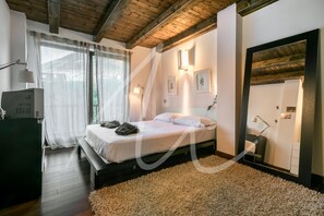 A bedroom with a bed, bedside lamps, a mirror, and a large window with curtains. - Forcanada (Vielha e Mijaran)