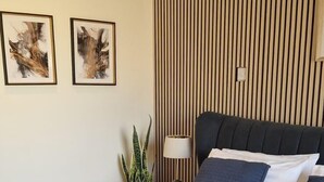 A hotel room with a bed, a nightstand, a lamp, and two framed artworks on the wall.