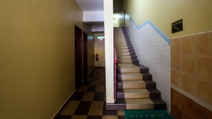 A hallway with a checkered floor, a staircase with a red handrail, and a sign indicating room numbers 402 to 405. - OYO 89549 Casavilla Hotel (city Centre) Taiping (Taiping)