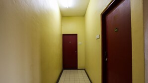 A narrow hallway with yellow walls and a tiled floor, leading to a red door with a number plate. - OYO 89549 Casavilla Hotel (city Centre) Taiping (Taiping)
