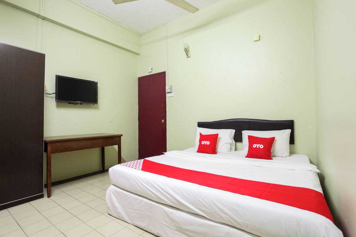 Une chambre d’hôtel équipée d’un lit, d’un téléviseur fixé au mur, d’un bureau et d’une armoire.
