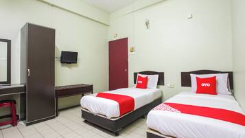 A hotel room with two beds, a desk, a wardrobe, and a TV.