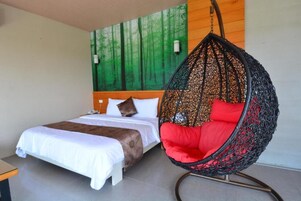 A bedroom with a bed, a hanging chair, and a wall with a green forest mural.