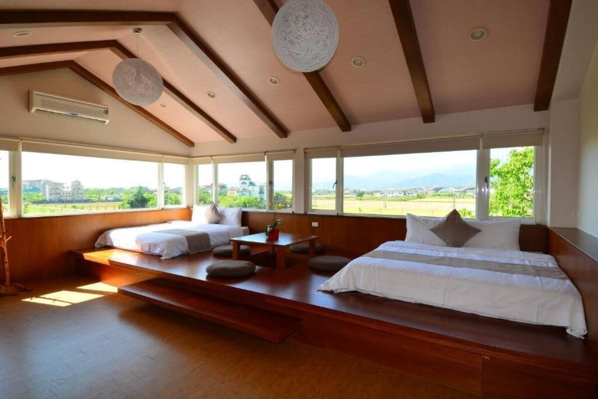 A spacious bedroom with a large bed, a smaller bed, and a seating area with a view of the outdoors.