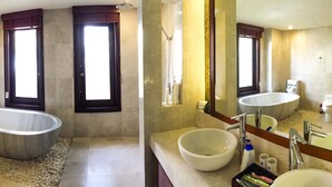 Un baño con una bañera independiente, un inodoro y un lavabo con espejo.