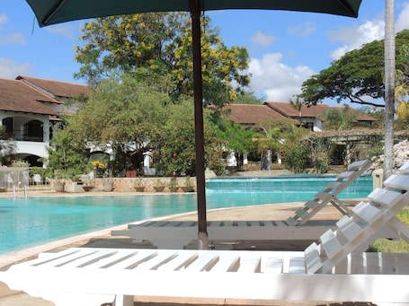 Una piscina al aire libre, sillones reclinables de piscina