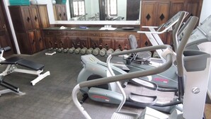 Un gimnasio con máquinas de cardio, mancuernas y un espejo.