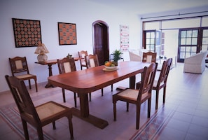 A dining area with a wooden table and chairs, a fruit bowl, and patterned wall art.