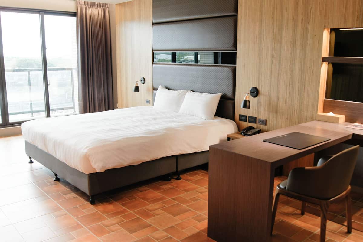 A modern hotel room with a large bed, a desk, and a chair.