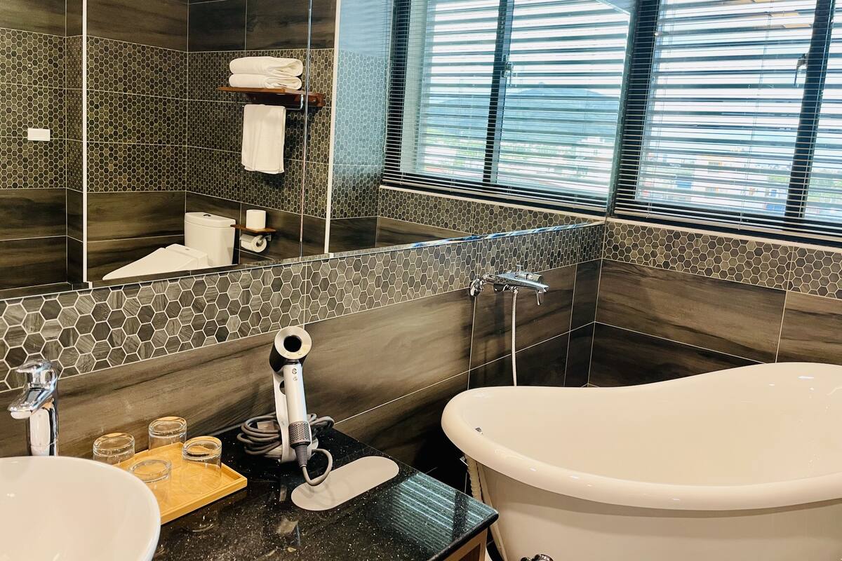 A modern bathroom with a large bathtub, a vanity with a sink and mirror, and a shower area.