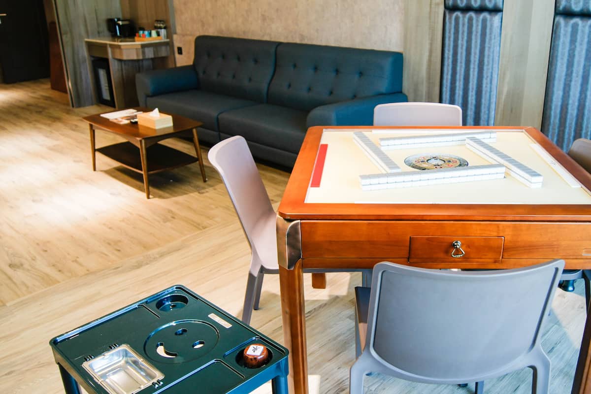 A room with a wooden table, chairs, a small table with a tissue box, a sofa, and a coffee machine.