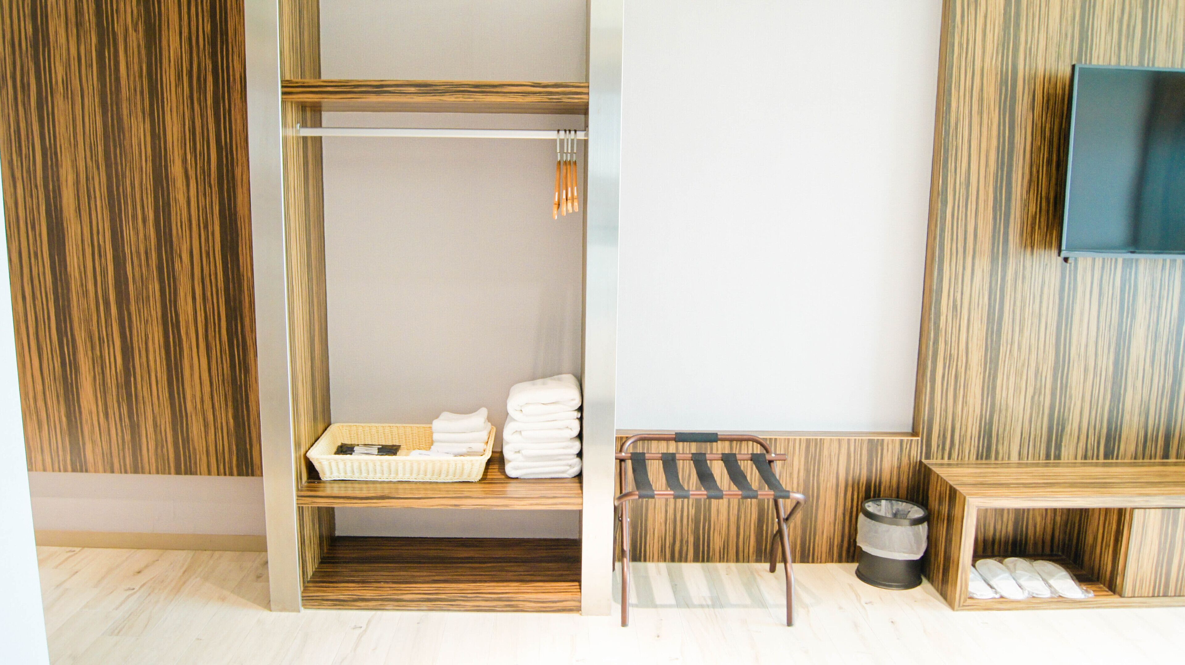 A bathroom with a wooden vanity, a towel rack, and a trash bin.