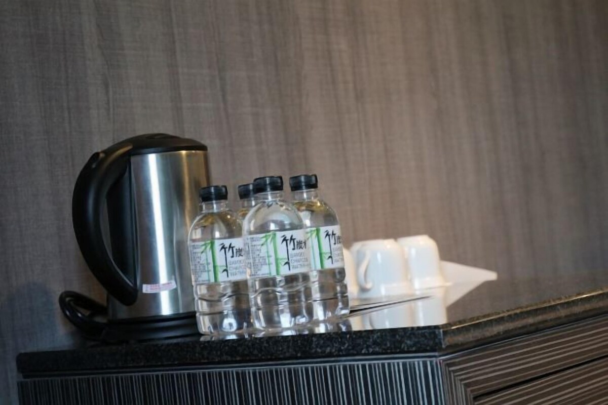 Una encimera con una tetera de acero inoxidable, tres botellas de agua y un recipiente blanco.