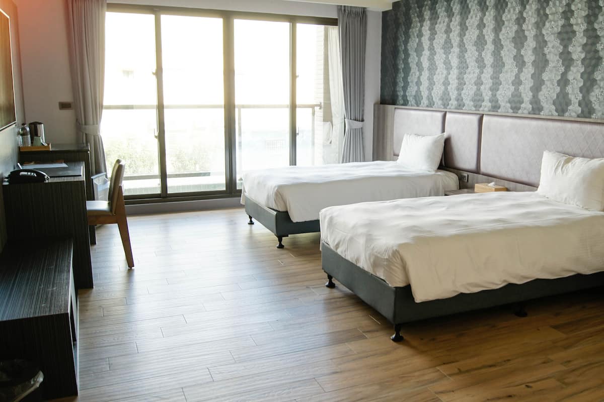 A hotel room with two beds, a desk, and a chair.