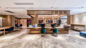 A modern hotel lobby with a reception desk, seating area, and a staircase leading to upper floors. - Zhangjiagang Suning Auraya Hotel (Suzhou)