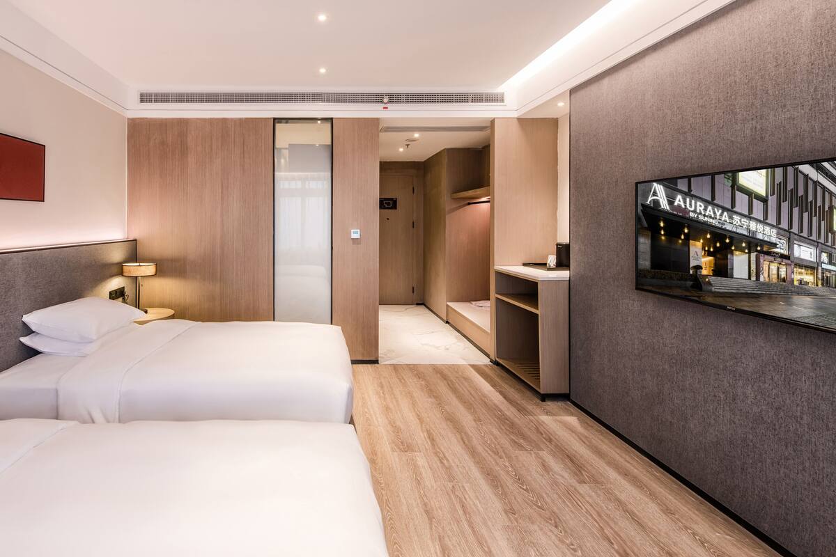Une chambre d’hôtel avec deux lits, un téléviseur fixé au mur et un dressing.