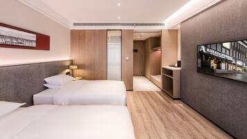 A hotel room with two beds, a TV mounted on the wall, and a walk-in closet.