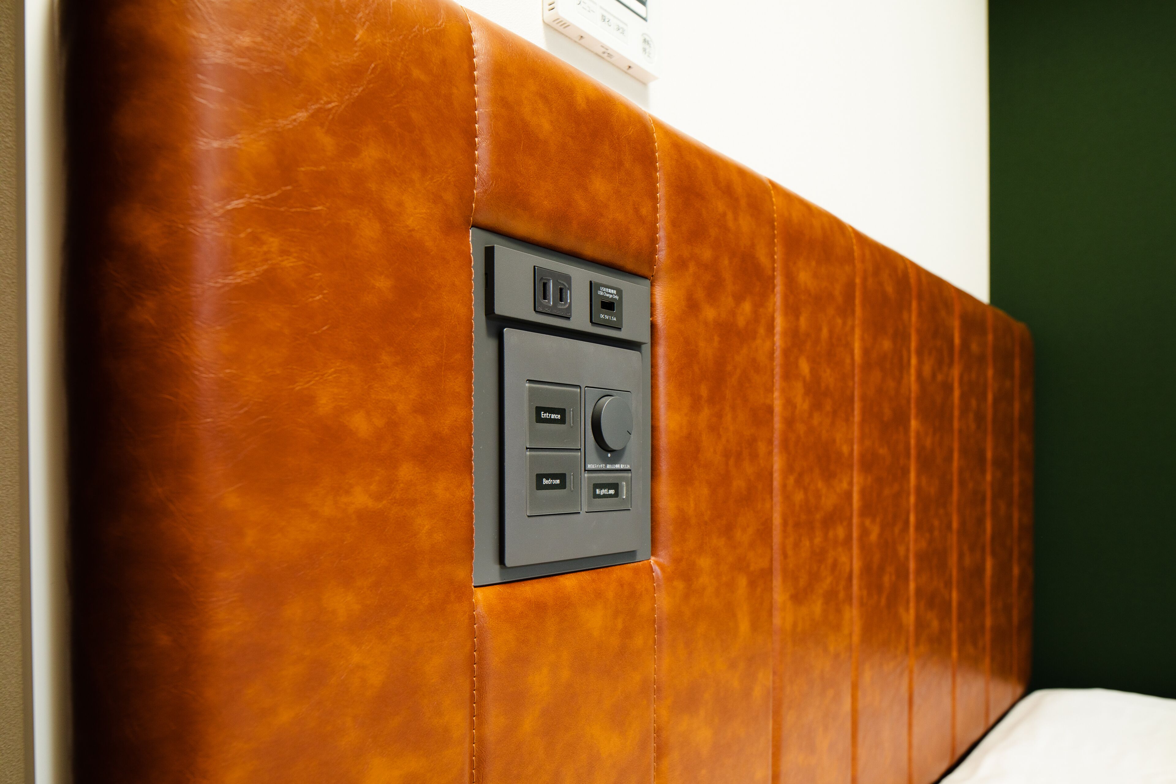 Parede com painel de controle com várias tomadas e interruptores, indicando um espaço funcional provavelmente usado para carregar dispositivos ou controlar os sistemas do quarto.
