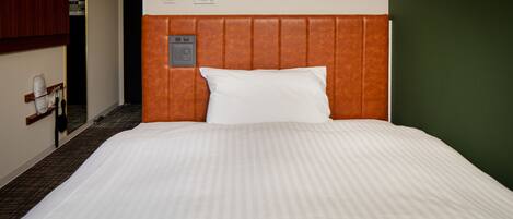 Una habitación de hotel con una cama grande, un cabecero con panel de control y un armario de madera.