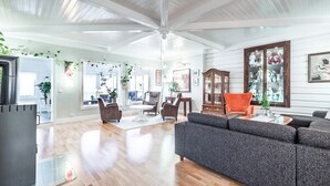 Een ruime woonkamer met een grote grijze hoekbank, houten vloeren en een plafondventilator.