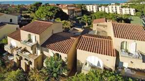 Uma área residencial costeira com edifícios de telhado em terracota, varandas com móveis de exterior e vista para o mar.