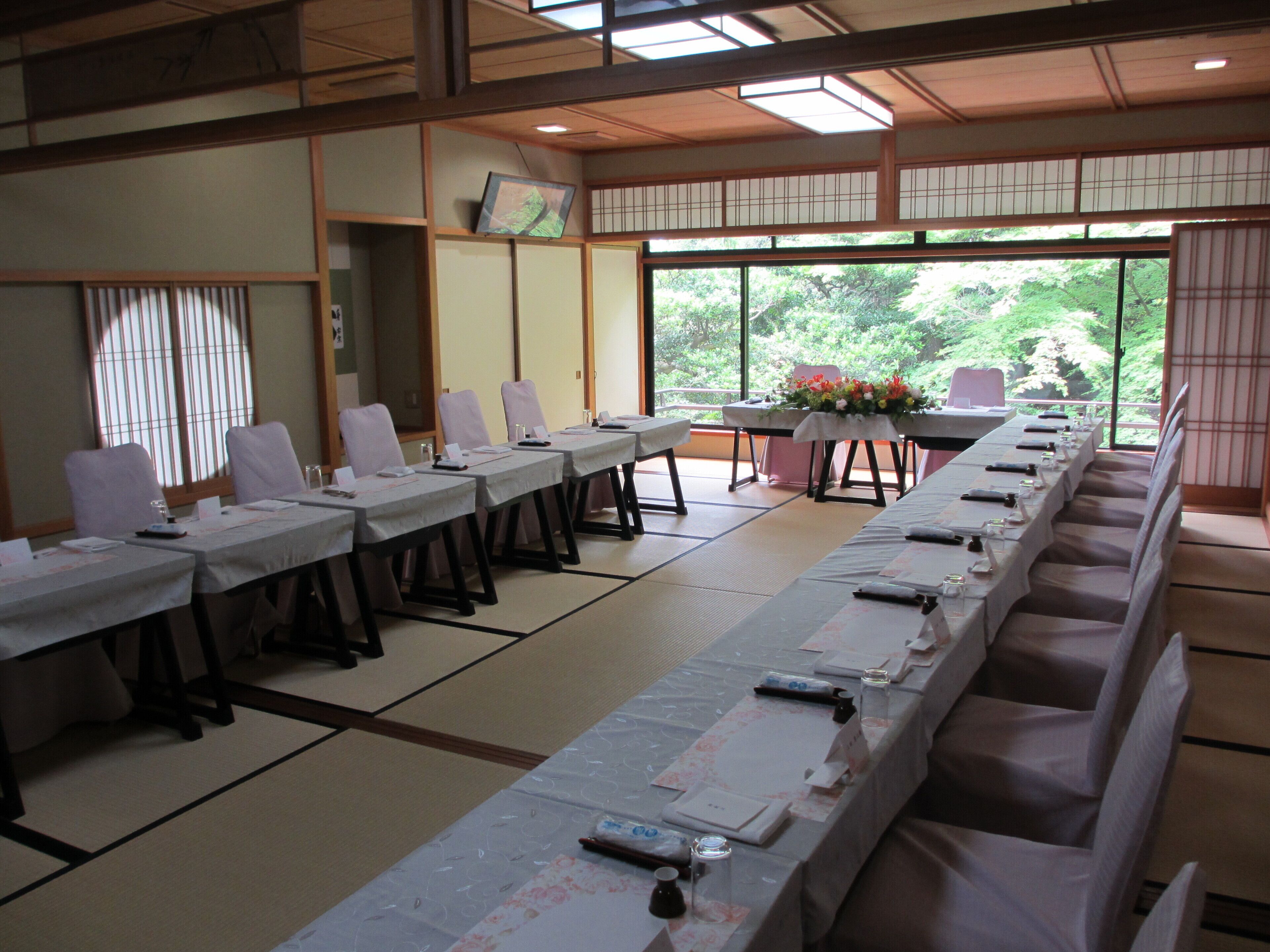 A traditional Japanese-style meeting room with tatami flooring, long tables, and chairs.