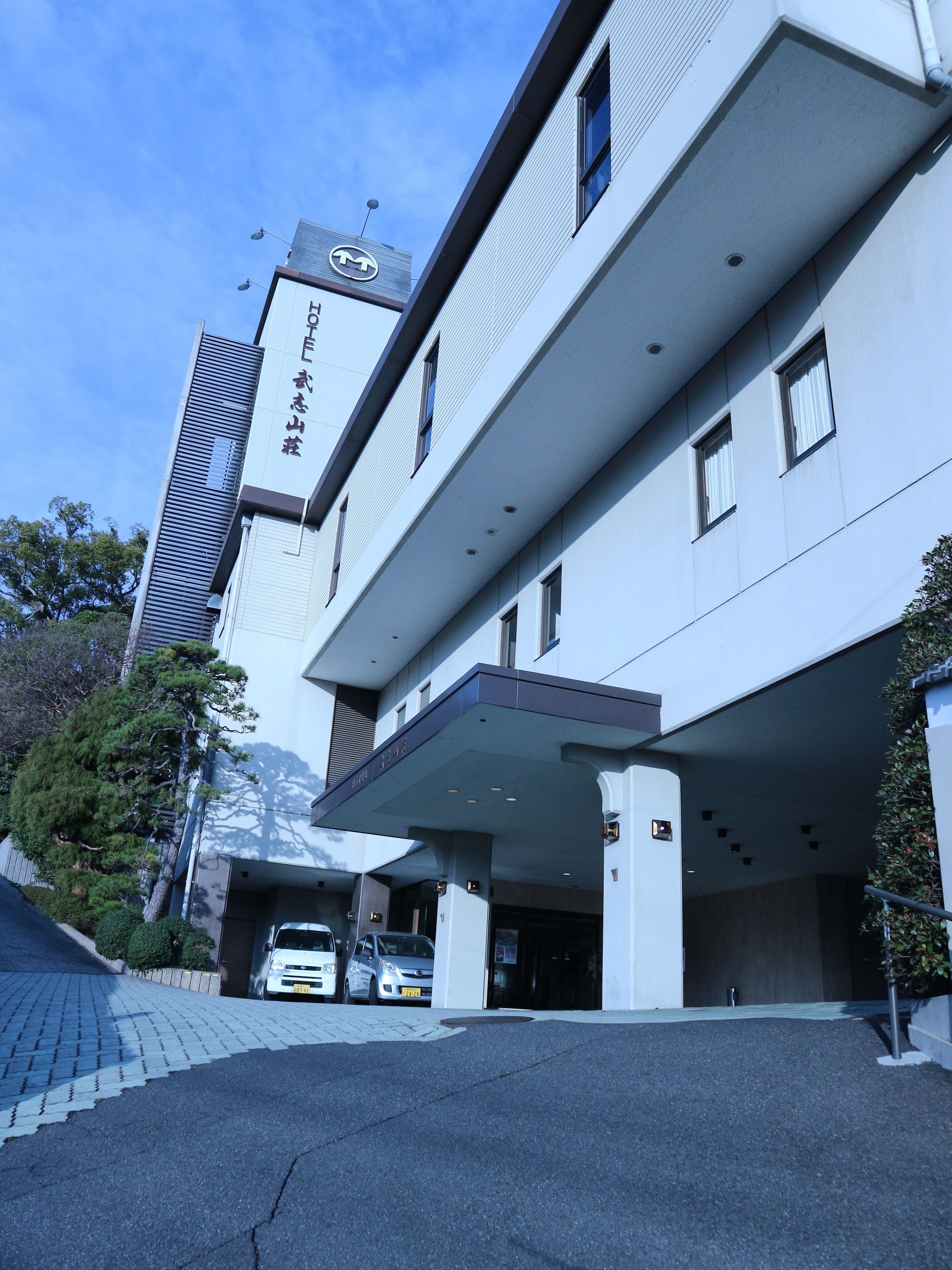 A modern building with a flat roof and a covered entrance area.