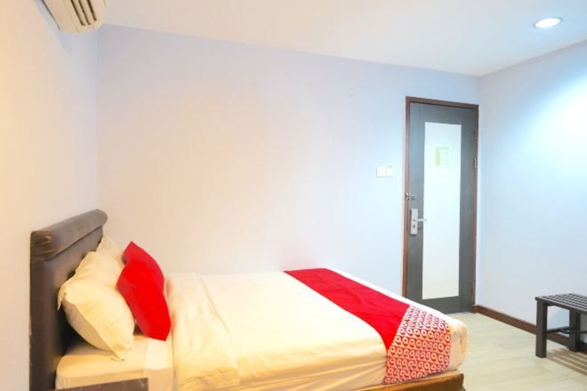 A hotel room with a bed, a bench, and a door.