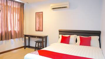 A hotel room with a bed, a desk, and an air conditioning unit.
