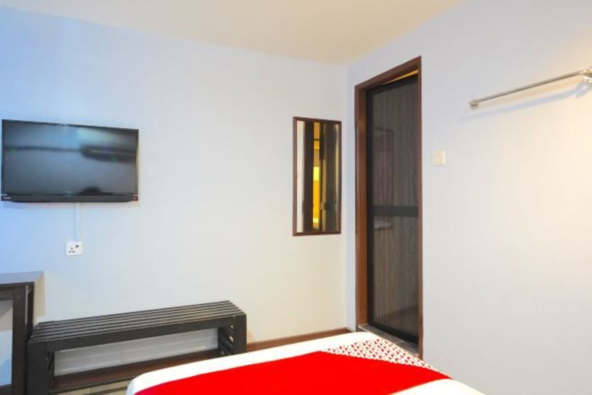 A bedroom with a bed, a TV mounted on the wall, a window, and a door.