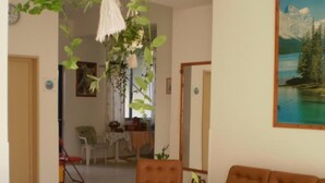 A living room with a brown sofa, a coffee table, and a hanging plant. - Pension Gina (Troizinia)