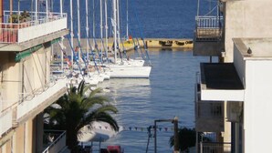 A marina with several sailboats docked, a palm tree, and buildings with balconies overlooking the water. - Pension Gina (Troizinia)