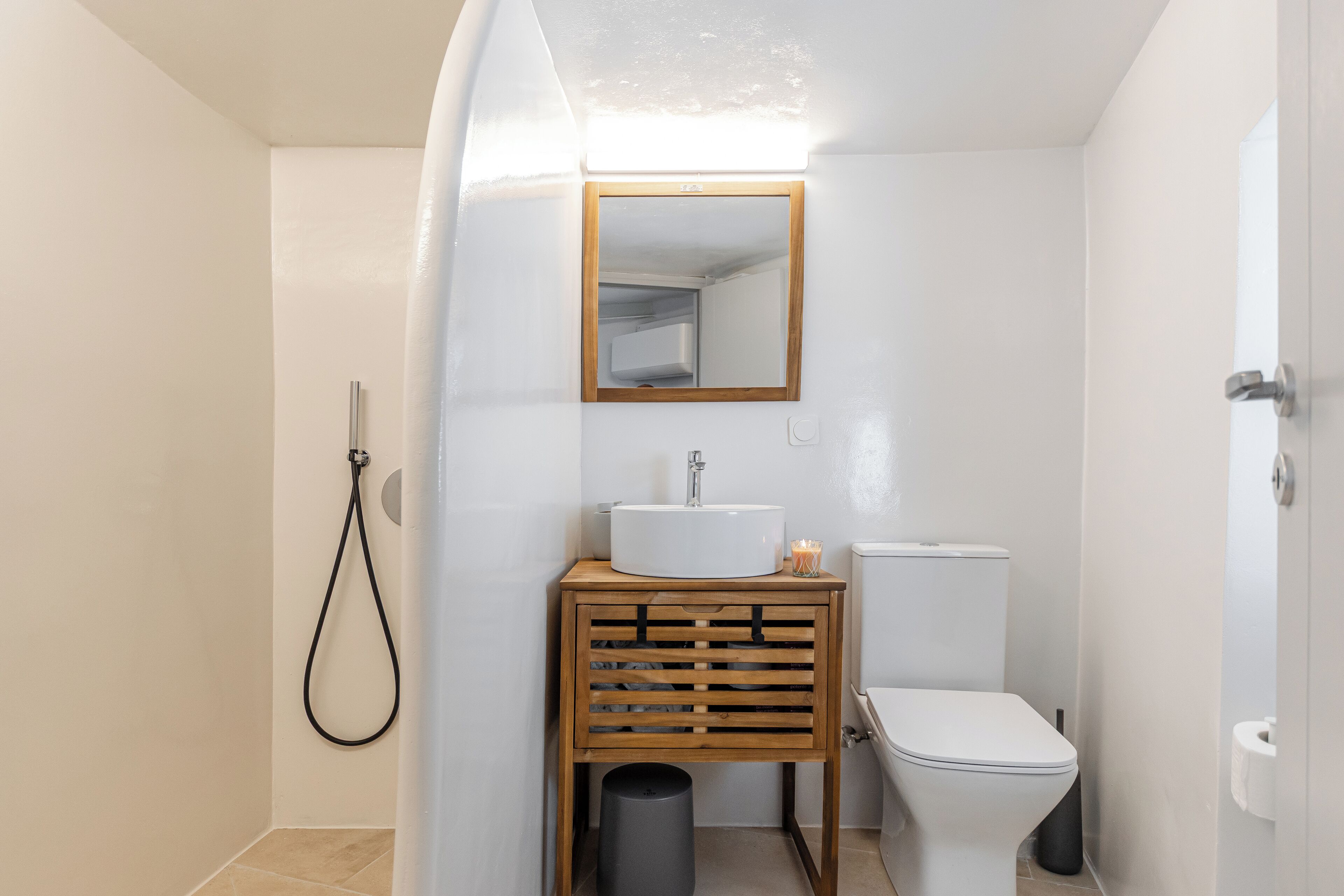 A compact bathroom with a white sink, wooden vanity, and a toilet.