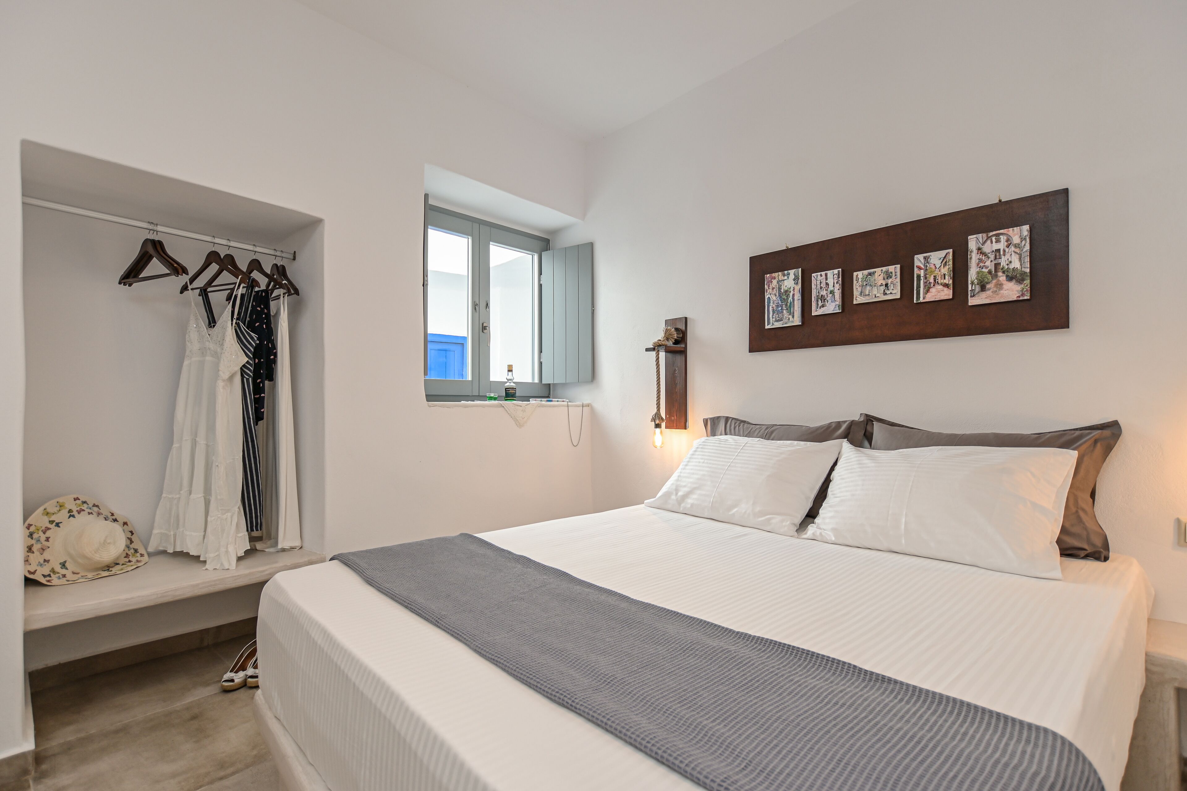A bedroom with a bed, a wardrobe, a window, and wall art.