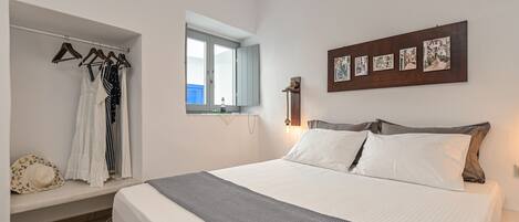 Een slaapkamer met een bed, een kledingkast, een raam en decoratieve muurkunst.