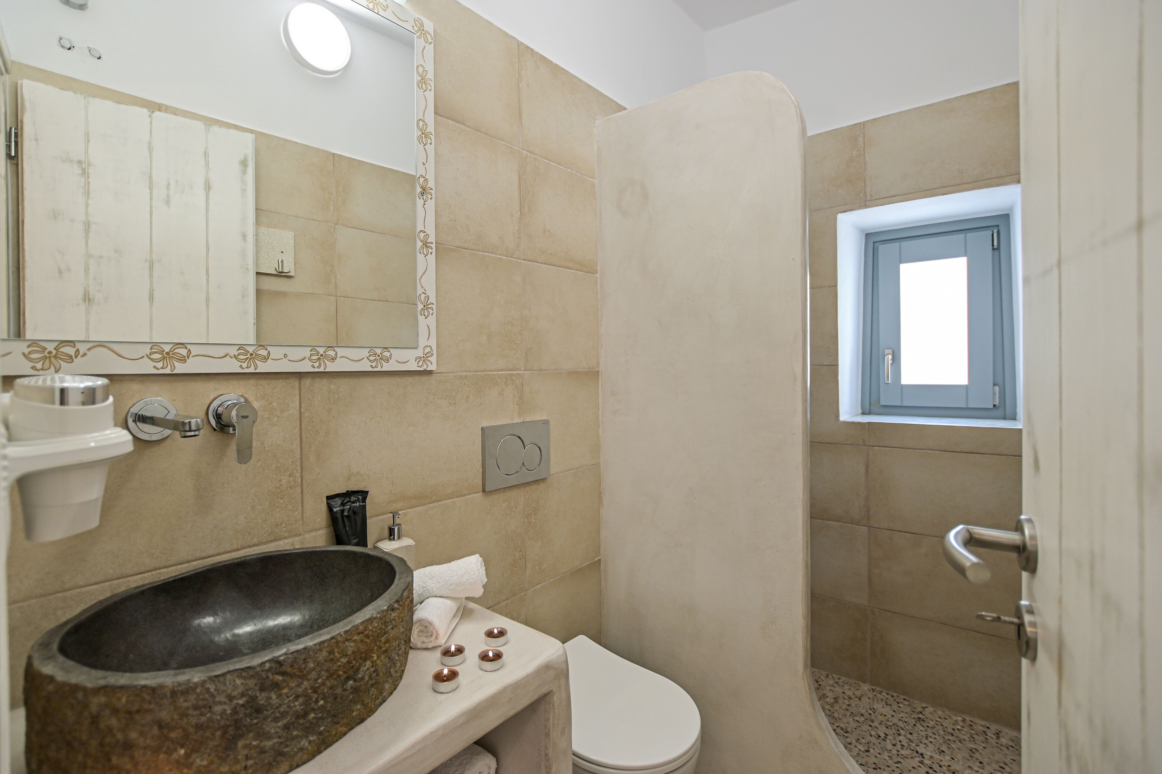 A bathroom with a stone sink, white toilet, and a shower enclosure.