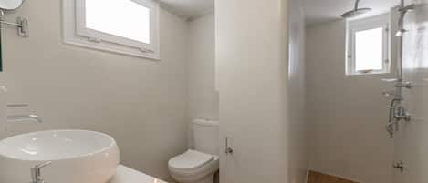 A modern bathroom with a large sink, toilet, and shower area.