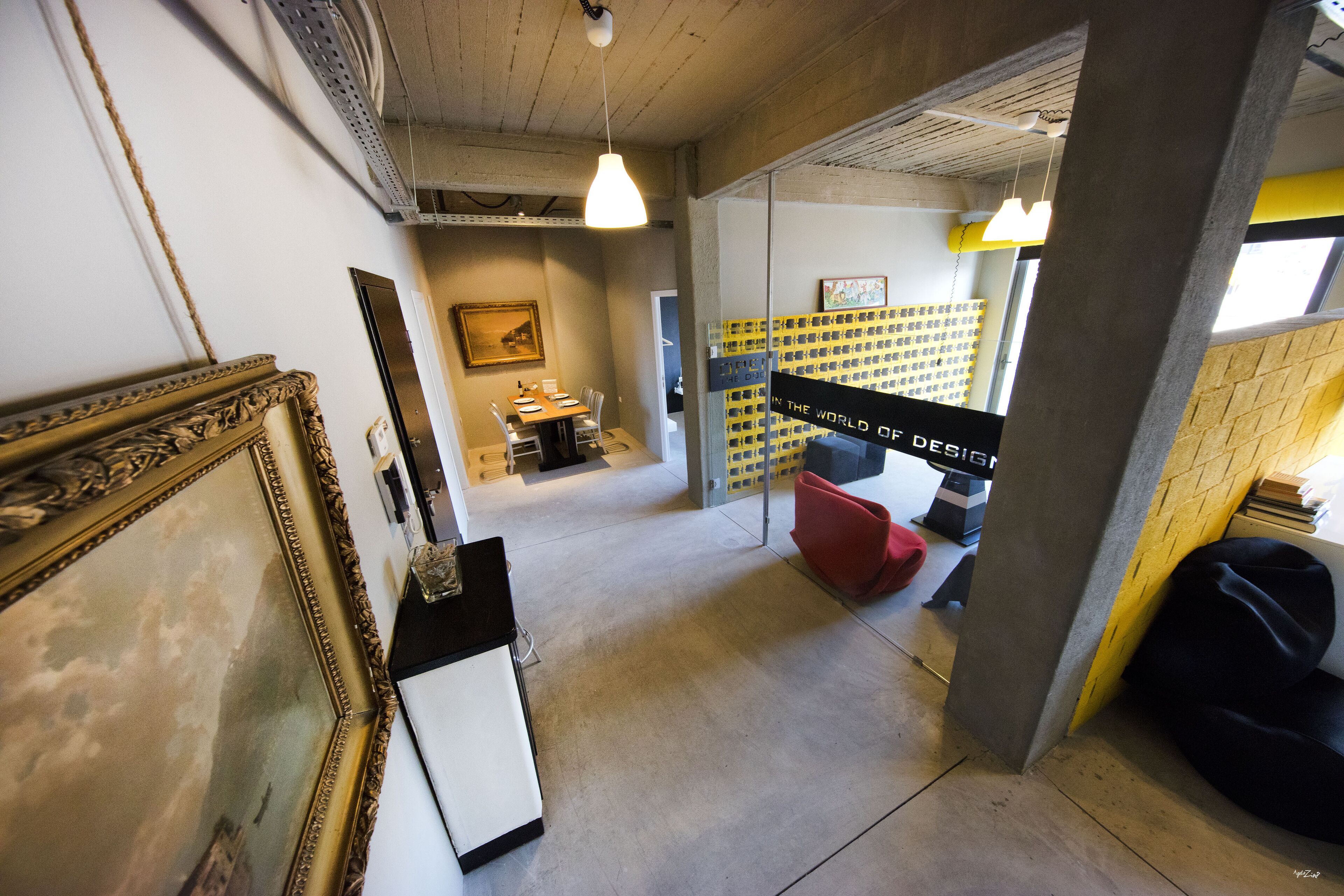 A corridor with a framed picture, a desk, chairs, and a bookshelf.