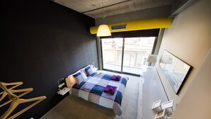 Ein modernes Schlafzimmer mit einem großen Bett, einem Fenster mit Blick und einer besonderen gelben Decke.