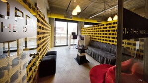 Ein modernes Interieur mit Glastrennwand, Wand mit Schwarz-Weiß-Muster, grauem Sofa und rotem Sessel.