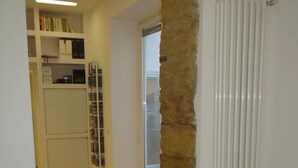 Un corridoio con pavimento in legno, termosifone bianco e una colonna in pietra.