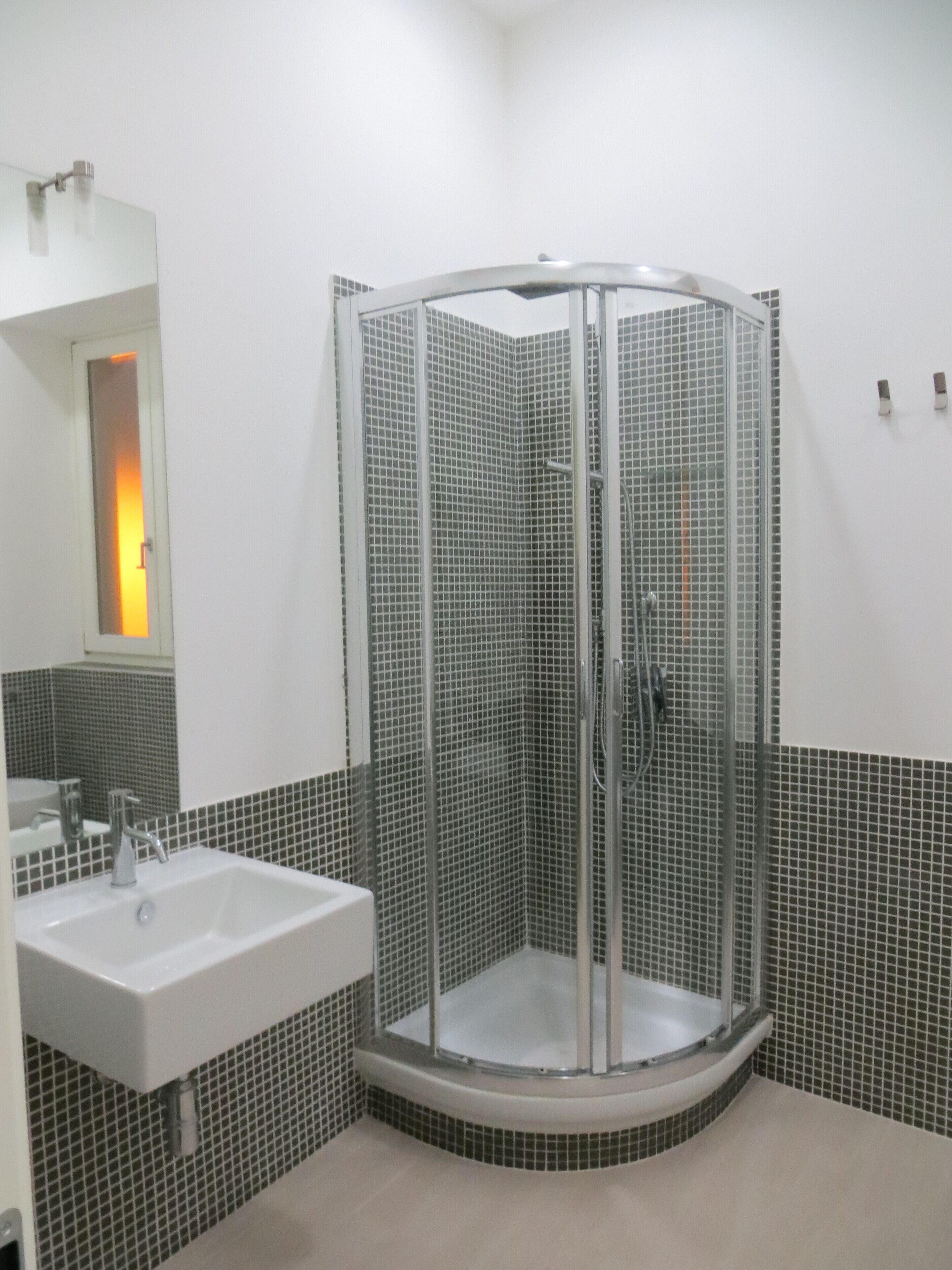 A modern bathroom with a glass-enclosed shower, a sink, and a mirror.