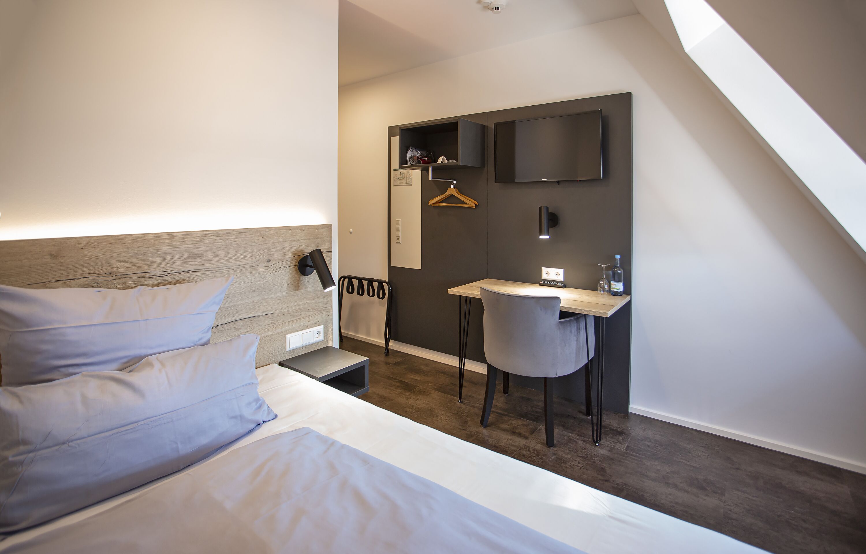 Een moderne hotelkamer met een bed, een bureau en een stoel.