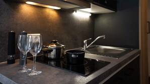 A modern kitchen with a built-in stove, a sink, and two wine glasses on the counter. - Drexels Parkhotel am Schloss (Krumbach)