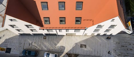Une vue aérienne d’un bâtiment doté d’un toit rouge, de nombreuses fenêtres et d’une façade blanche.