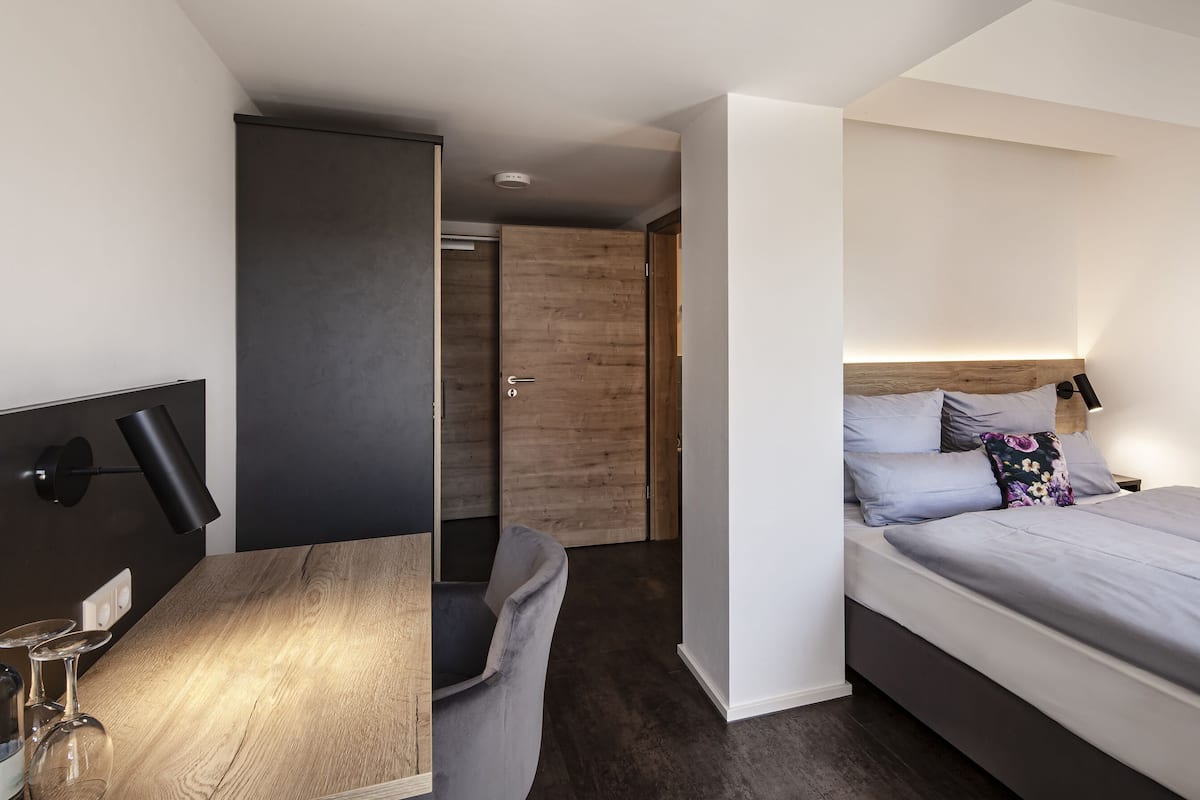 A modern bedroom with a bed, bedside table, and a desk with a lamp.