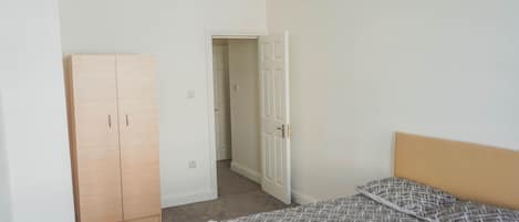 Un dormitorio con cama, armario y puerta que da a otra habitación.
