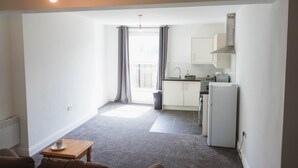 A compact living space with a kitchenette, a small dining area, and a view through a window. - 1 Bed Flat in Pedestrianized High Street (Dover)