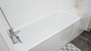 A modern bathroom with a white bathtub, a showerhead, and patterned tiles. - 1 Bed Flat in Pedestrianized High Street (Dover)
